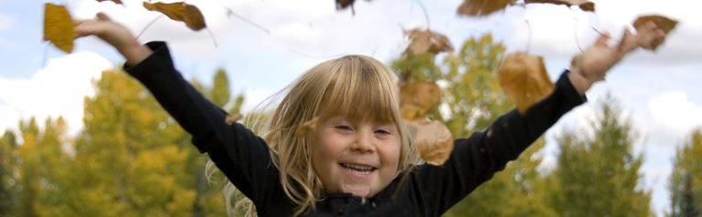 Mädchen/ Kind Ein kleines Mädchen wirft Herbstblätter in die Luft und lächelt freudig.